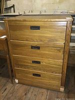 Front view of wood dresser showing four drawers and black recessed handles.