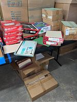 Table with multiple boxes stacked and scattered containing hanging folders and various office folders with red and white Office Depot labeling, brown folders, and assorted classification folders.