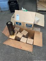 Box opened showing multiple smaller boxes inside along with one visible cylindrical cup dispenser with gold-colored base and top.