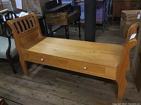 Front angle of wood bench with two drawers under seating area on wooden floor.
