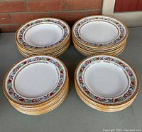 Four stacks of antique Minton dinner plates with colorful Italian fruit border and gold lustre trim