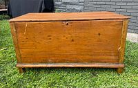 Front view of antique pine blanket box showing rectangular shape, dovetailed construction, minor surface scratches, and wear.