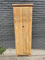 Full front view of tall, skinny antique pine cupboard with closed double doors and metal latch.