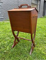 Side view of the antique maple sewing basket showing tapered shape and stand legs.