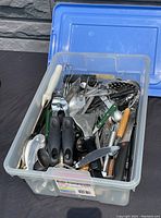 Image showing a plastic bin filled with assorted flatware and kitchen utensils such as spoons, forks, knives, peelers, spatulas, can openers, and whisks.