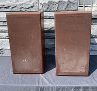 Pair of vintage B&W loudspeakers viewed from the front, showing wear to brown cloth covers.