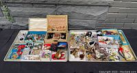 Full view of all jewelry items spread across two large trays and framed by two jewelry boxes containing additional pieces
