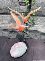 Front and angled view of vintage John Perry flamingo sculpture featuring two pink flamingos on metal stands attached to a marbled moon egg-shaped base.