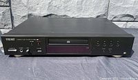 Front view of black Teac compact disc player with top surface showing light scratches.
