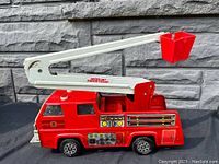 Side view of vintage red Tonka fire rescue truck with extendable white boom arm and red bucket, detailed stickers on side panels