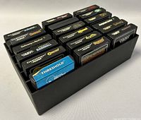 Eighteen vintage ColecoVision and ADAM video game cartridges stored in a black organizer tray, showing label sides with various game titles from the 1980s.