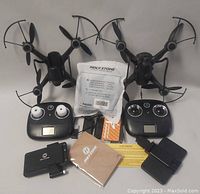 Two Holy Stone 6 Axis Gyro drones with controllers, batteries, user manual, tools and charger arranged for photo.