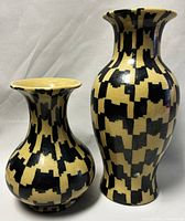 Photo showing front and side views of two ceramic vases, a smaller bulbous one and a taller curvaceous one.