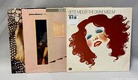 Four vinyl records, showing covers of Bette Midler, Amy Holland, Queen City Kids, and Jane Siberry albums, arranged with some overlapping.