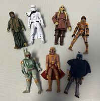 Seven varied Star Wars action figures arranged on a flat surface.