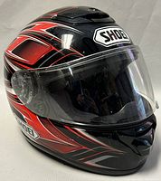 Front view of black and red SHOEI full face motorcycle helmet with clear visor down showing visor scratches and helmet graphics.