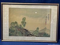 Framed Chinese watercolor painting on silk showing landscape with traditional buildings and trees under moonlight.