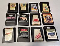 Top-down photo of twelve vintage Coleco Vision game cartridges showing labels with game titles and artwork.