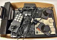Top-down photo of two numeric keypad controllers, two joystick controllers, and cables inside a cardboard box.