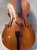 Front view of cello showing spruce top, bridge, strings and f-holes