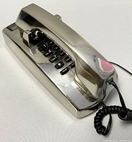 Side angle view of the vintage phone showing metallic handset and numeric keypad with standard digits and function keys.