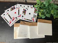 Two sets of four coasters each, one set featuring marble tone stone with wooden accent, the other set featuring playing cards showing Aces.