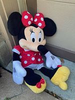 Full view of Minnie Mouse stuffed doll sitting, showing red polka dot dress, yellow shoes, and facial details
