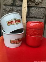 Two white Gourmet Poutine ceramic bowls stacked, showing logo and size comparison with ruler.