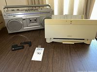 JVC boombox stereo radio cassette recorder and Apple StyleWriter II printer together with Apple tools on a wooden surface.