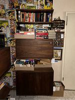 Full view of shelving unit assembled on wall showing stacked cabinets and shelves loaded with books