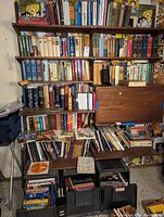 Books arranged on multiple shelves and in boxes, assorted mostly hardback and paperback with a variety of titles and subjects.