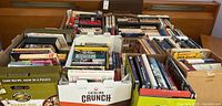 Wide view of various books in cardboard boxes showing a variety of book types and sizes