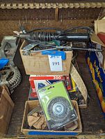 Box containing black handheld Dremel rotary tool with attached power cord, visible metal attachments and accessories in the box.