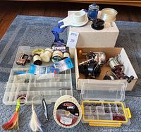 Full lot overview showing fishing reels, multiple spools of fishing line, tackle boxes containing hooks and weights, and several fishing lures.