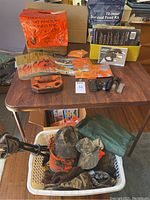 Overview of hunting headwear in basket and survival food kit on table
