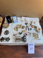 Wide shot displaying all jewelry items laid out including brooches, hair clips, earrings, necklaces, and pendants.