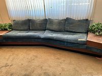 Front view of entire teal upholstered sofa showing integrated wooden side tables at each end
