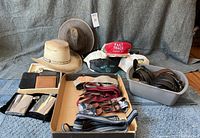 Overview of hats, wallets, suspenders, and belts laid out including cowboy and Henschel hats