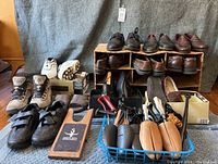 Overall view of men's shoes, shoe stretchers, shoe horns, boot jack, and laces arranged on floor and shelves.