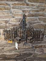 Frontal view of mounted metal fishing village sculpture showing detailed huts, boats, and masts on a stone wall background.