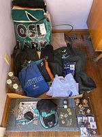 Photo showing various San Jose Sharks hoodies, sweatshirts, bags, collectible pins, hats, and bottles arranged on floor and shelf.