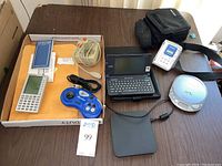 Photo of the full lot arranged on a table with all devices visible including controllers, flight computer, portable computer, cd and cassette players, and carrying cases.