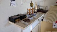 Shelf showing the whole lot of Asian decorations including fossil cases, wooden animal figurines, ceramic trinket cases, and small objects