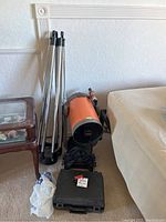 Group shot of orange telescope tube, aluminum tripod, Dobsonian base and accessory case