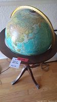 Front side of globe showing Asia and surrounding countries with wooden stand and brass meridian