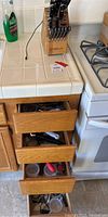 Wooden drawers partially open, showing more kitchen utensils and cutlery stored inside