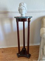 Full view of the wooden pedestal with green marble top and white marble female bust on it.