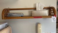 Full view of the largest rattan wall shelf mounted on wall with papers and tissue box on shelf surface.