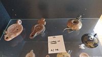 Display of five vintage handcrafted oil lamps including two painted ceramic lamps and three brown clay/ceramic lamps in traditional shapes