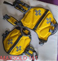 Front side view of two yellow dog lifejackets showing padded sections, grey cross logos, adjustable straps and buckles.